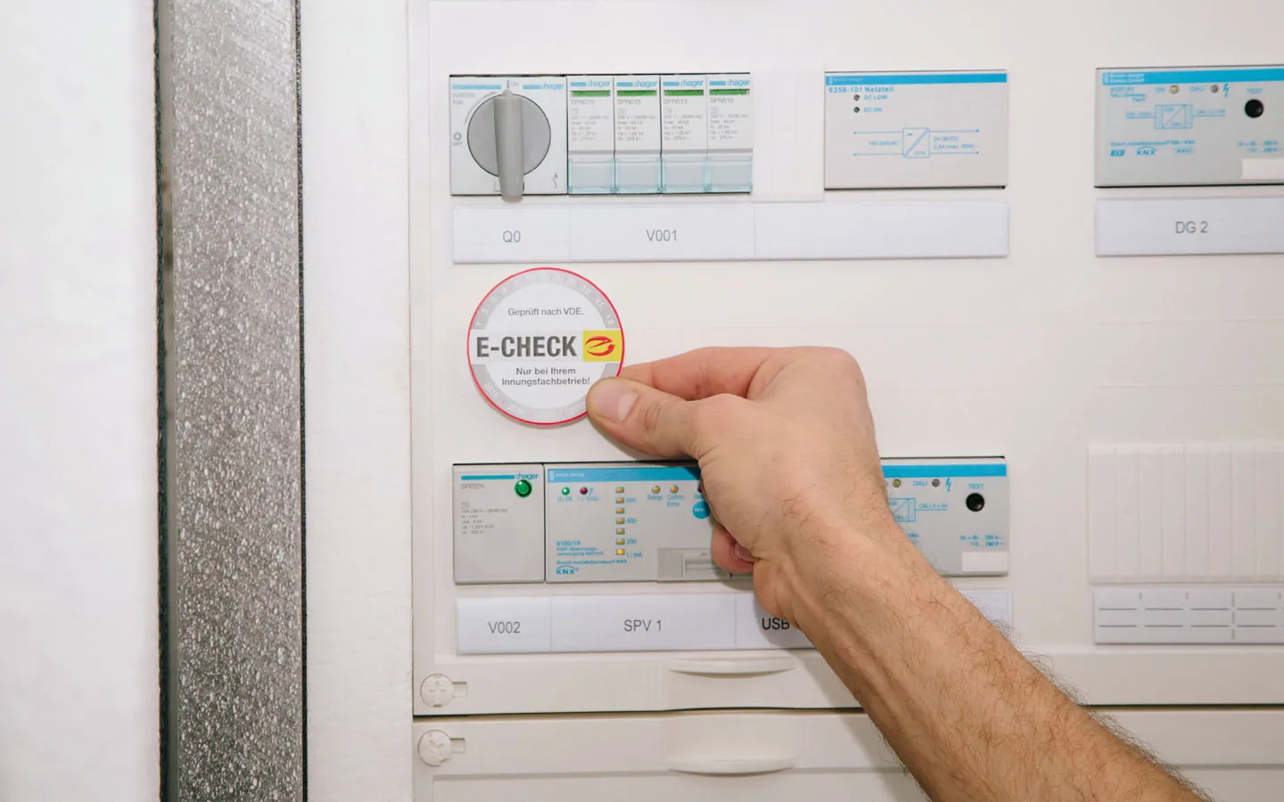 E-CHECK - Mitarbeiter klebt in der Verteilung die E-CHECK Plakette an · Elektro-Stock