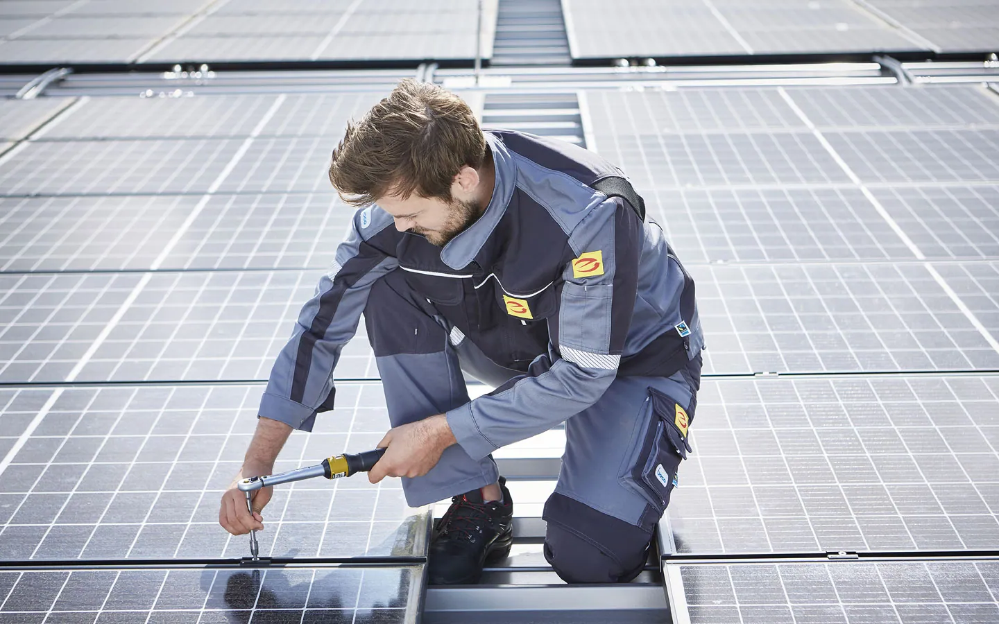 E-CHECK E-Mobilität - Mitarbeiter montiert auf dem Dach die neuen Solarmodule · Elektro-Stock