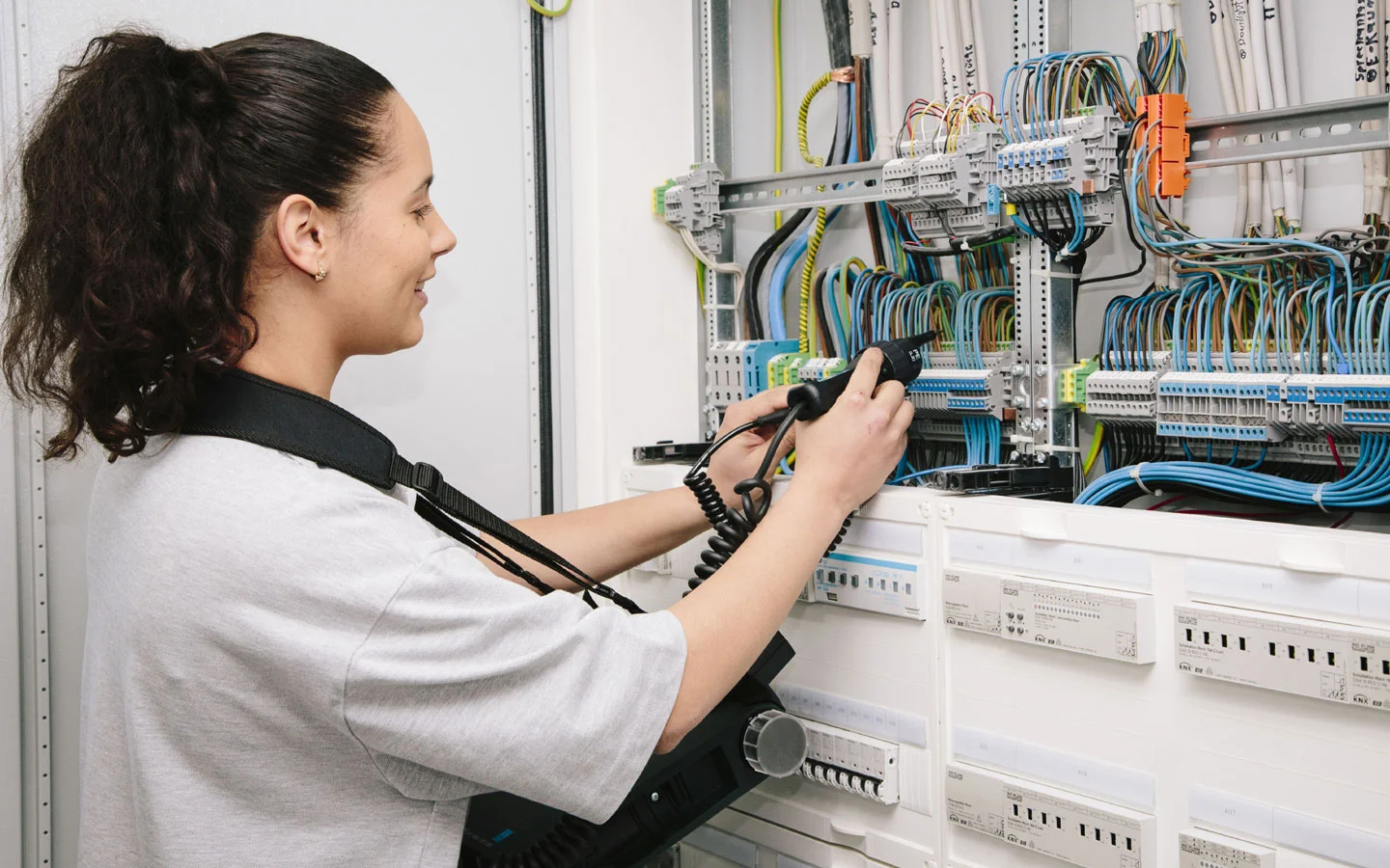 E-CHECK - Mitarbeiterin prüft im Schaltschrank mit einem Meßgerät · Elektro-Stock