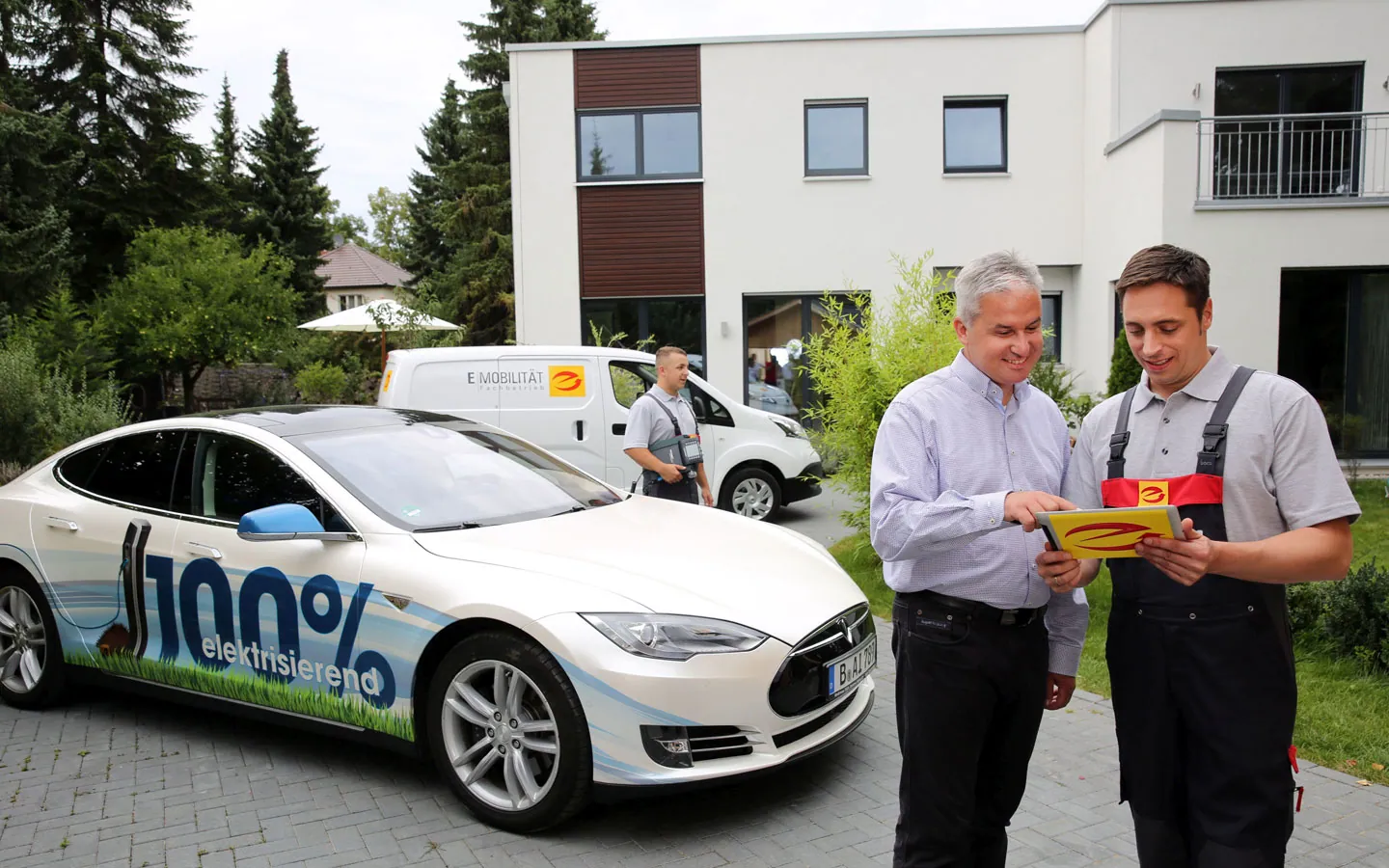 E-Mobilität - Mitarbeiter mit Kunden vor Elektrofahrzeugen 100% elektrisch · Elektro-Stock